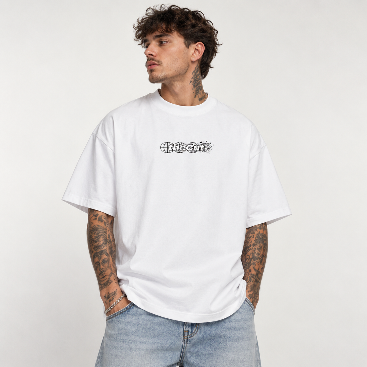 Model wearing theCut Globe tee in white, front view, with a small black theCut wordmark at the left chest.