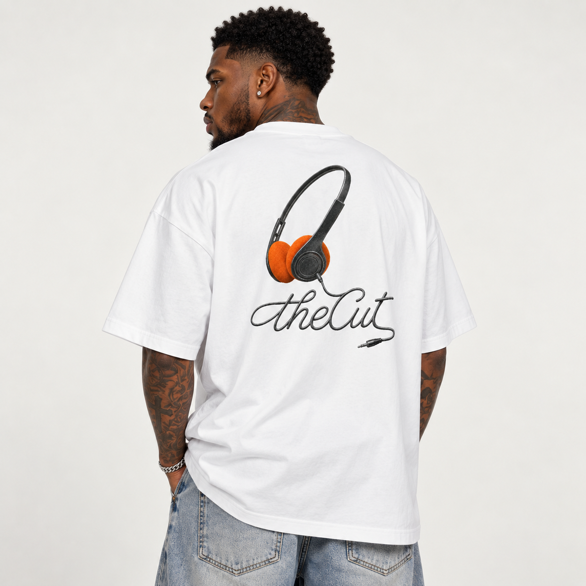 Model seen from behind wearing theCut Music tee in white, showing the orange headphones illustration and theCut script printed across the back.