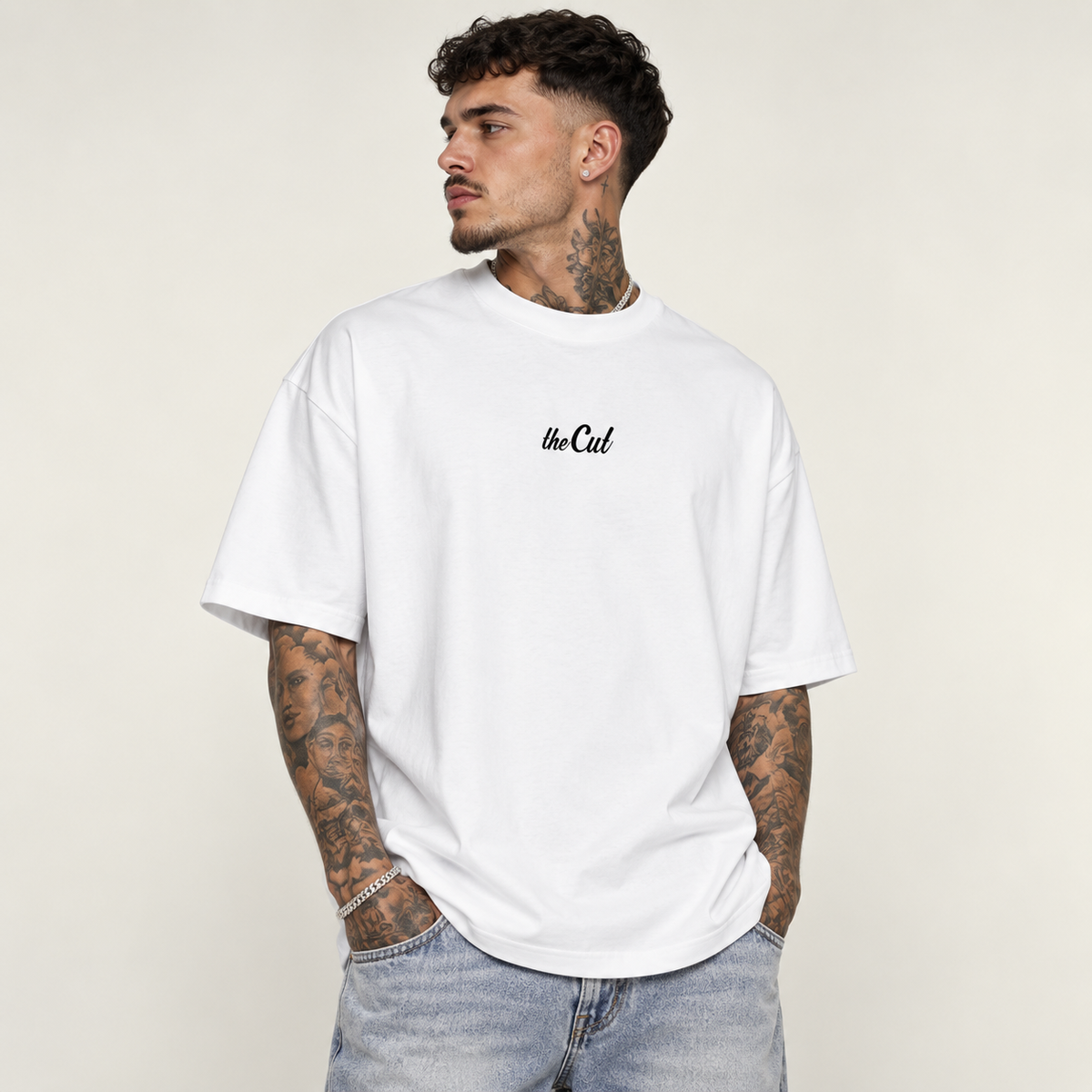 Model wearing theCut Fades Not Favours tee in white, front view, with a small black script logo at the left chest.