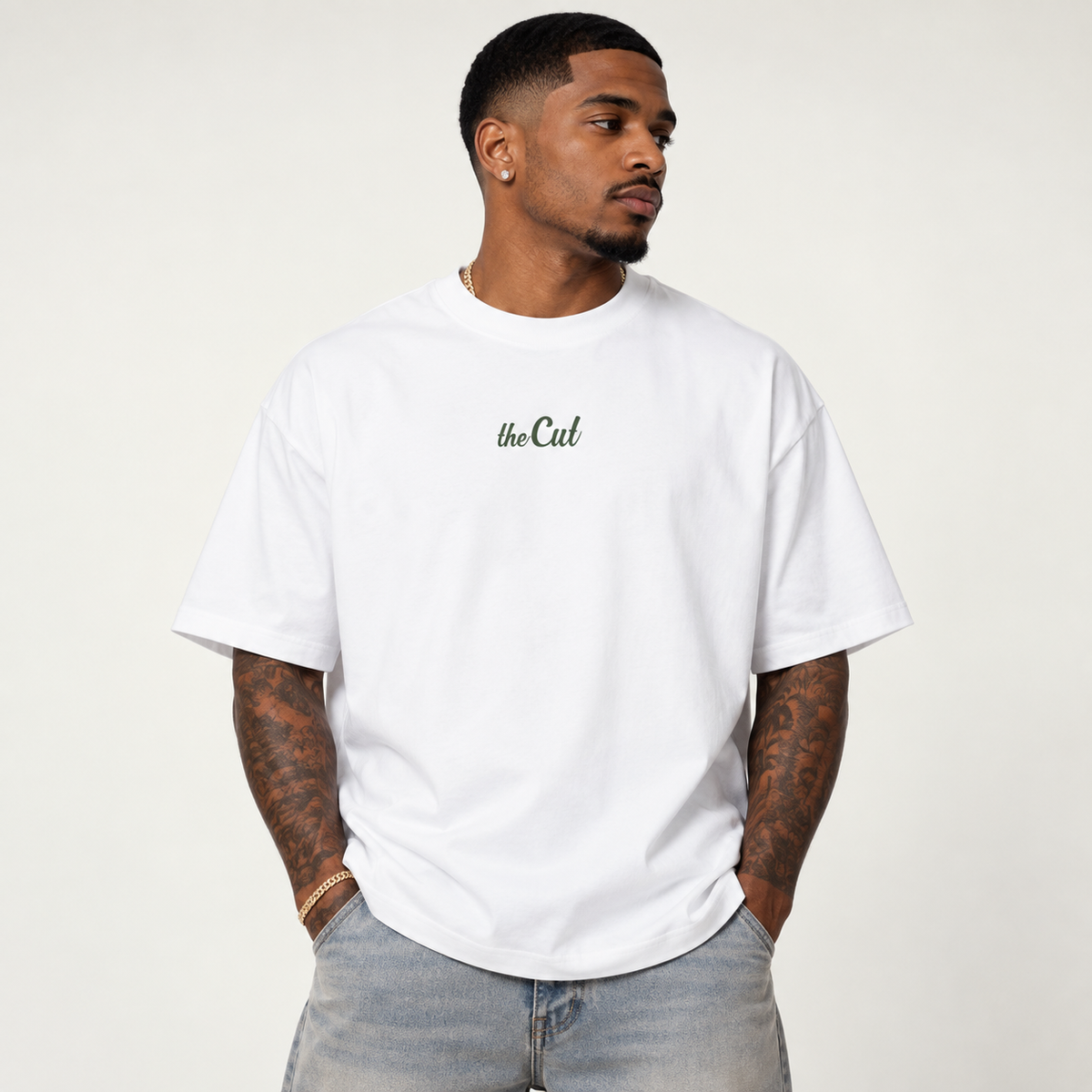 Model wearing theCut Fades Not Favours tee in white, front view, with a small green script logo at the left chest.