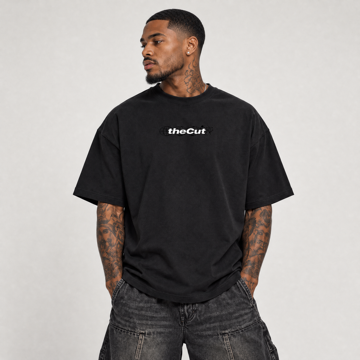 Model wearing theCut Globe tee in black, front view, with a small white theCut wordmark at the left chest.