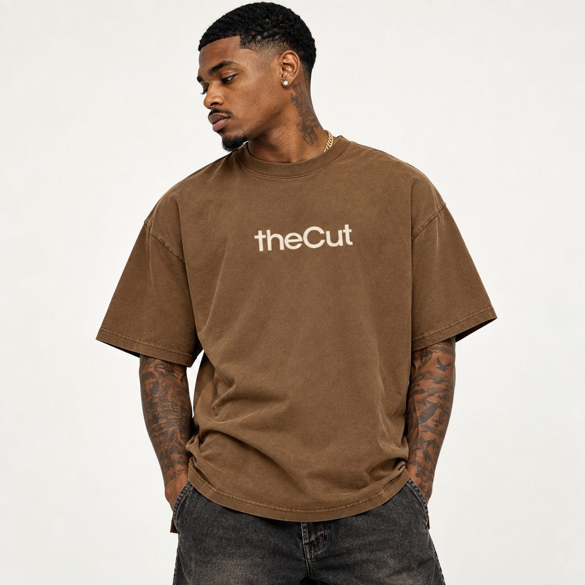Model wearing theCut tee in washed brown, front view, with a small cream theCut wordmark at the left chest.