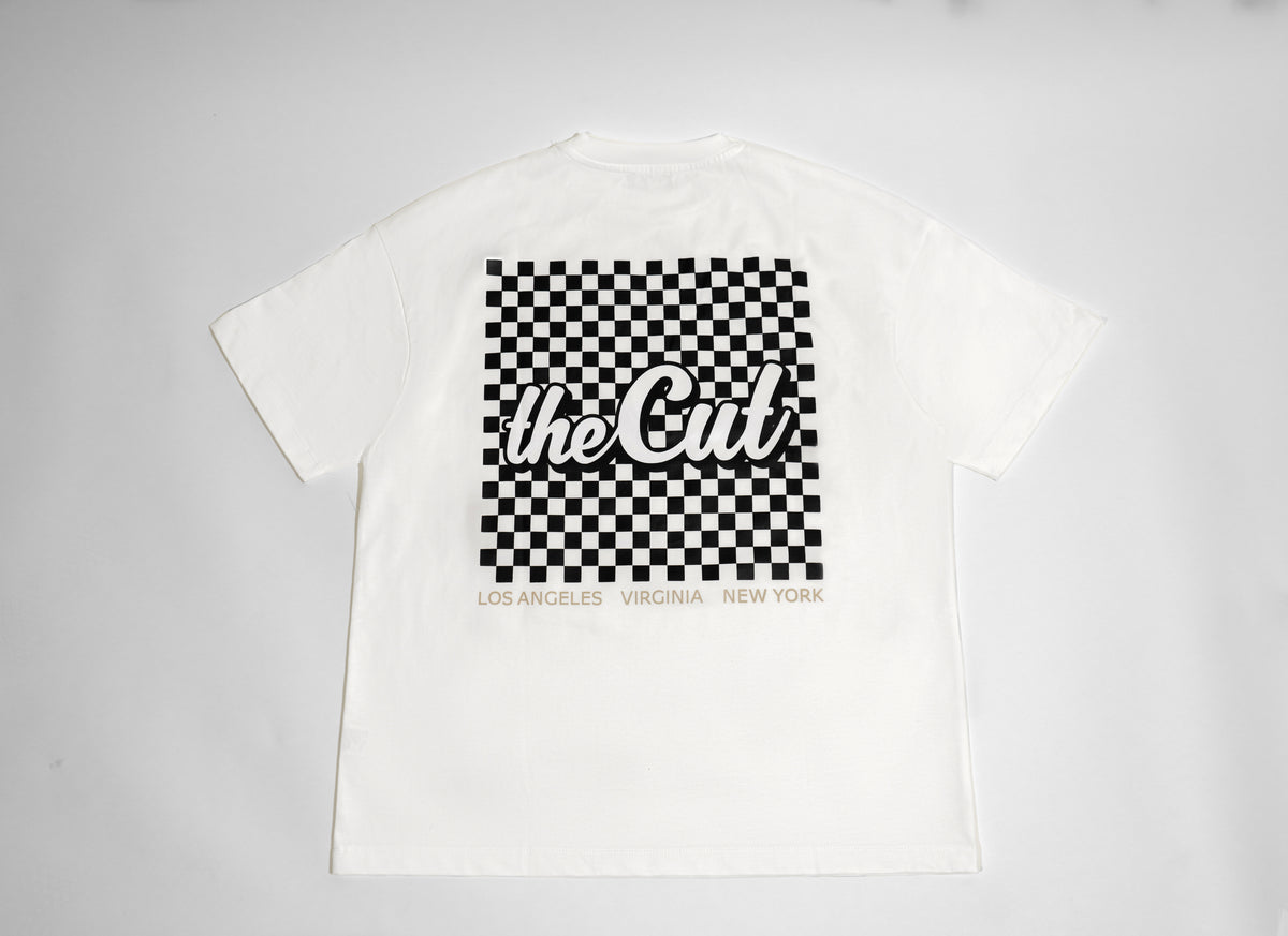 theCut Home Finish tee in white shown flat from the front, with a black and white checkerboard graphic and theCut logo.