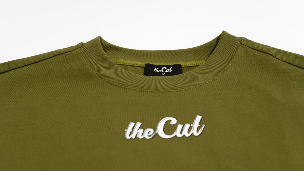 Close detail of theCut Stay Sharp tee in olive, showing theCut script logo.